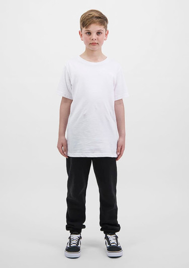 A child stands wearing a plain white t-shirt and black track pants, complemented by black and white sneakers.