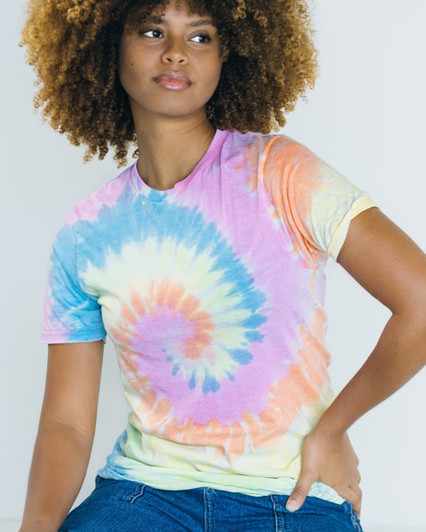 A woman models a Colortone® tie dye adult T-shirt featuring a spiral pattern in pastel colours of blue, pink, yellow, and green.