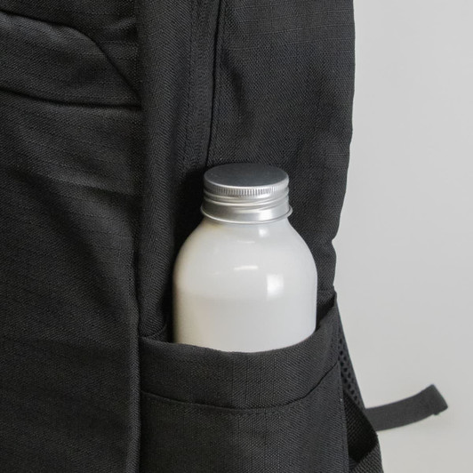 A black backpack pocket holds a silver-capped drink bottle, featuring a textured fabric design.