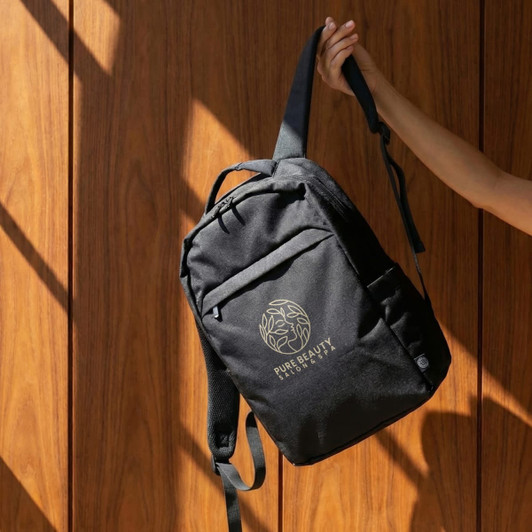 A black recycled backpack with a logo, displayed against a wooden background.