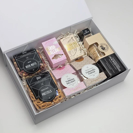A gift box featuring an assortment of sweets and snacks, including pretzels, marshmallows, Turkish delight, and fudge.