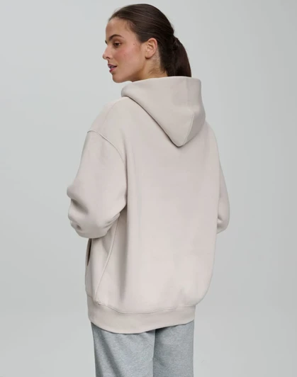 A unisex premium fleece oversized hoodie in a light beige colour, featuring a hood and a relaxed fit.