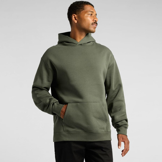 A man wearing an olive green hoodie featuring a front pocket and a hood, with a logo on the sleeve.