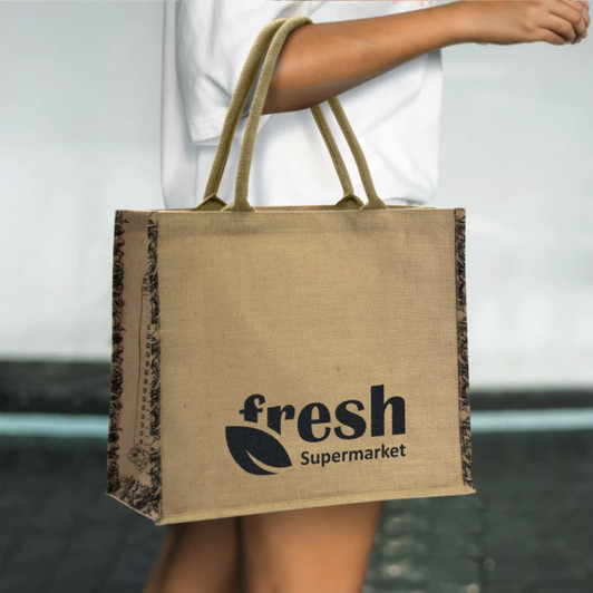A jute tote bag in natural brown with dark patterned sides and a logo on one side.