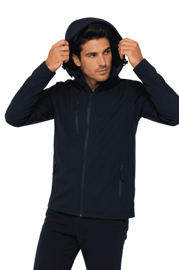 A man wearing a navy soft shell jacket with a hood, featuring zippered pockets and a fitted design.