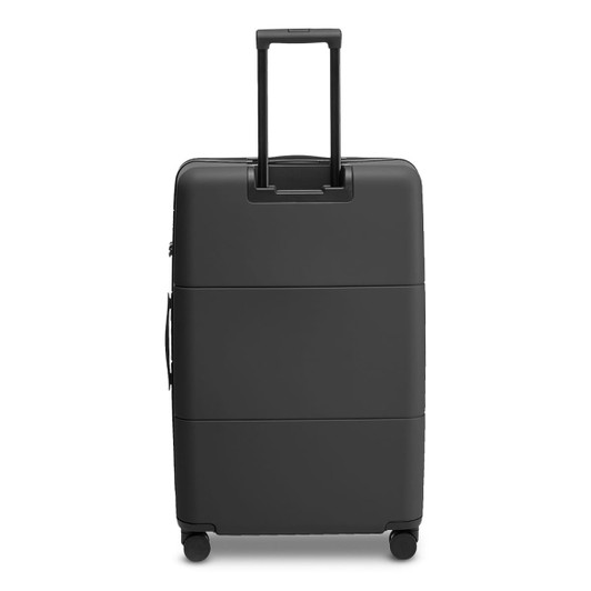 A large black suitcase with a retractable handle and wheels, featuring a smooth surface and an attached logo.