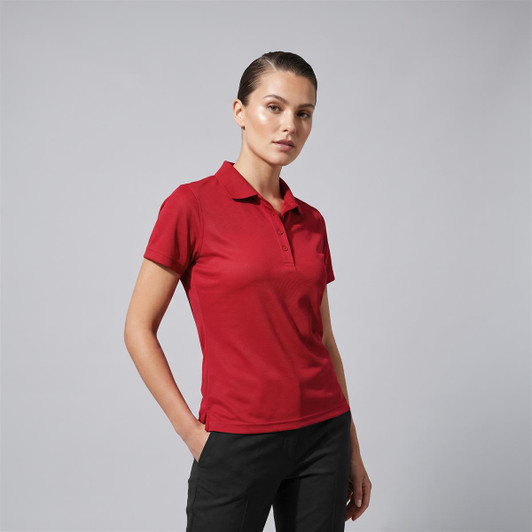 A red women's polo shirt displayed on a model with a neutral background, featuring a collar and short sleeves.