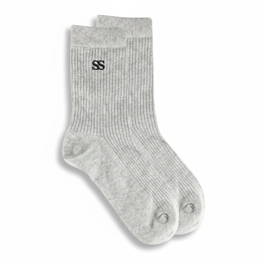 A pair of grey lounge socks featuring a ribbed texture and a logo on one side.