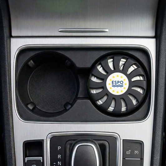 An air freshener in a circular black holder, placed in a car cup holder, featuring a logo.