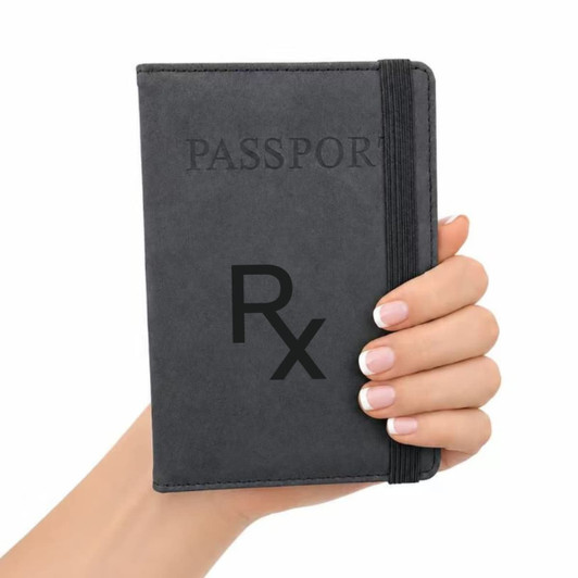 A grey passport wallet is held in a hand, featuring a band for secure closure and a logo on the cover.