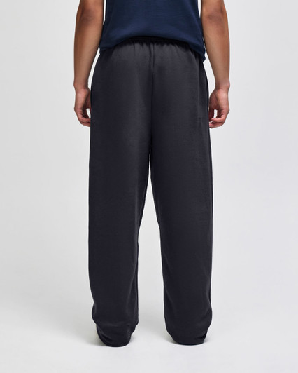 Open-bottom fleece pants in black, featuring pockets and a relaxed fit. Back view displayed.