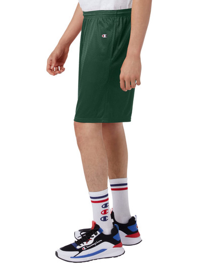 Green sports shorts with pockets, featuring a logo, displayed on a model alongside sneakers and socks.