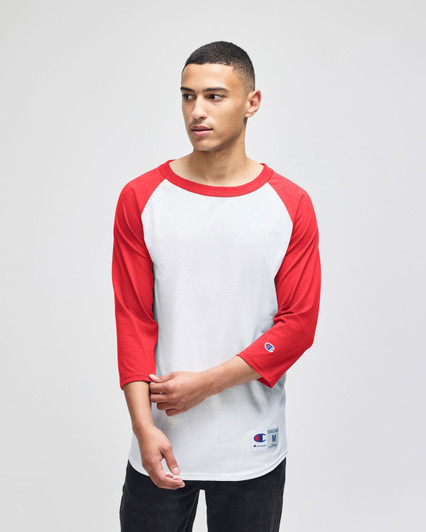 A raglan baseball T-shirt featuring a white body and red sleeves, worn by a model. The shirt has a logo.