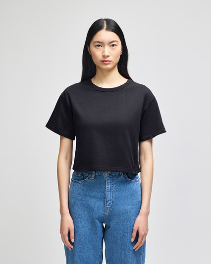 A black cropped short sleeve jersey t-shirt featuring a casual fit, displayed on a model wearing blue jeans.