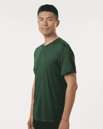 A man wearing a green performance t-shirt, featuring a fitted design and short sleeves. The shirt has a logo.