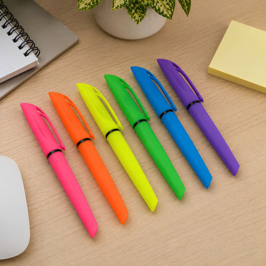 A set of six highlighter pens in bright pink, orange, yellow, green, blue, and purple, placed on a desk with stationery.