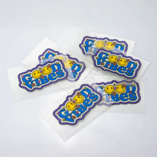 A collection of colourful stickers featuring playful designs and a logo on a white background.