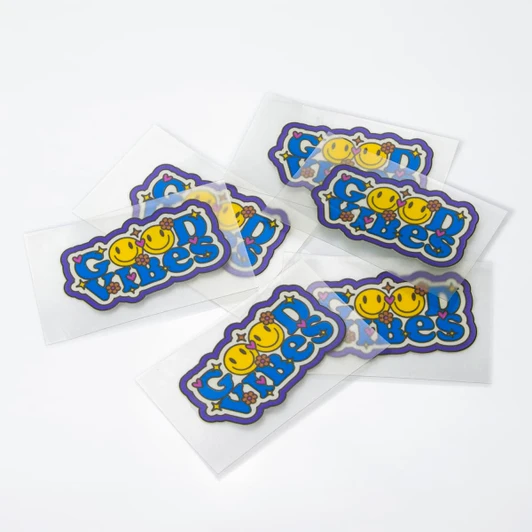 Colourful stickers featuring smiling faces and playful text, with a glossy finish, presented on a white background.