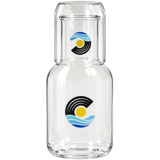 A glass carafe with a matching cup set, featuring blue and yellow wave and sun designs, includes branding.