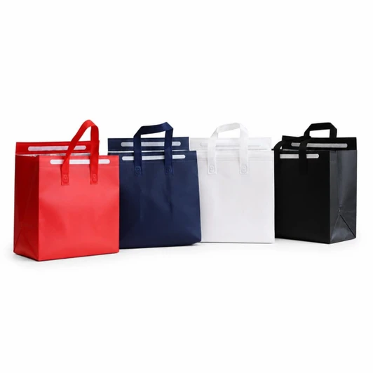 Four insulated reusable bags in red, navy, white, and black, featuring handles and a logo.