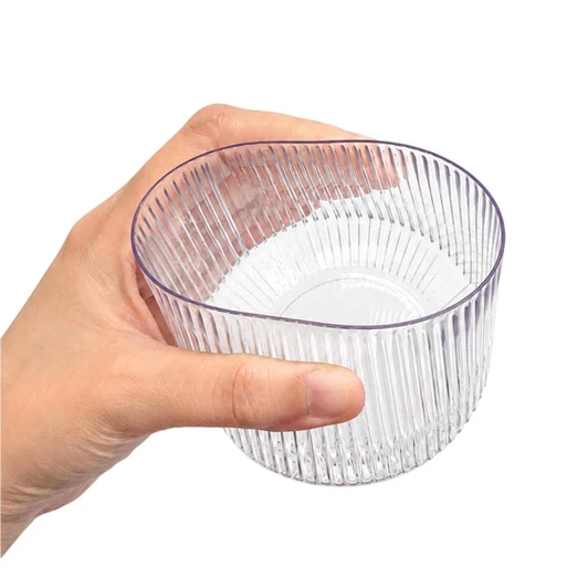 A clear, ribbed tumbler held in a hand, featuring a stylish design and a transparent appearance.