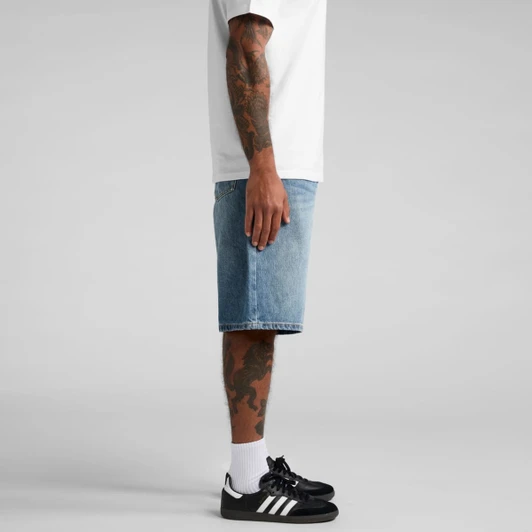 A pair of blue denim shorts displayed on a person, featuring a side view with black shoes and white socks.