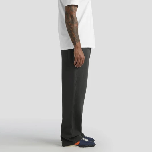 Faded cuffless track pants in dark grey, modelled with a white t-shirt and navy shoes. Contains a logo.