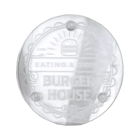 A clear round glass coaster with a logo design and four small feet for stability.