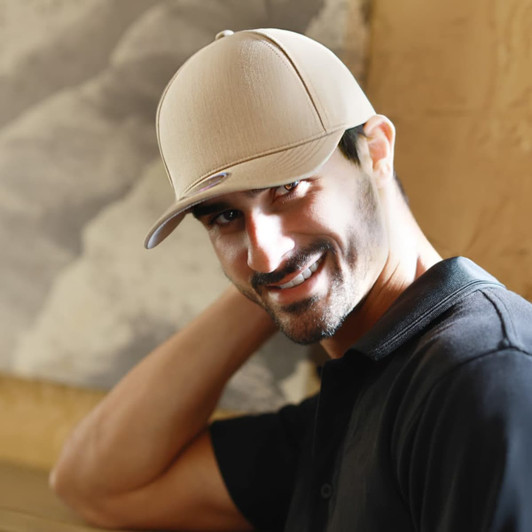 A beige cap with a logo, worn by a smiling man with a casual black shirt, set against a soft background.