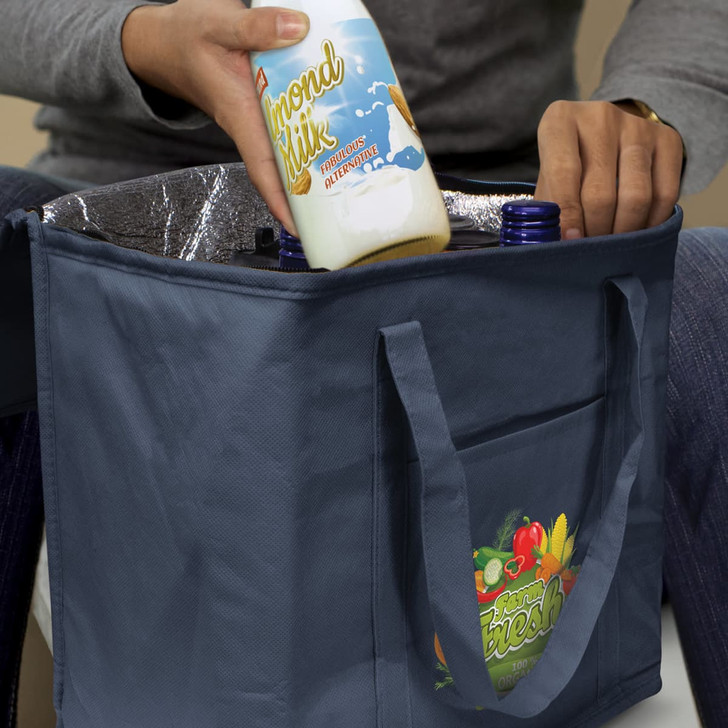A drink bottle is being placed into a navy cooler bag with an interior lining, featuring a logo.