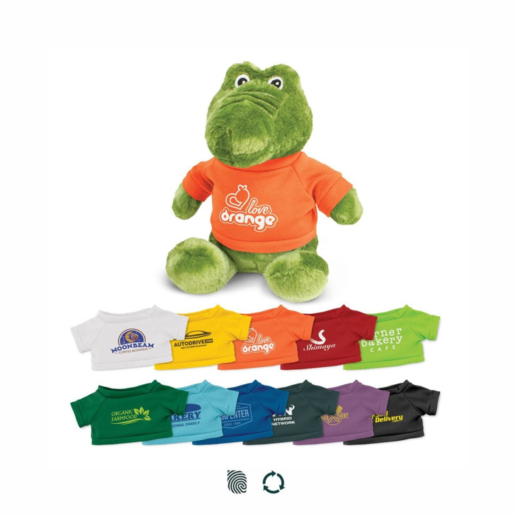 A green crocodile plush toy wearing an orange t-shirt, with a variety of smaller t-shirts in different colours below.