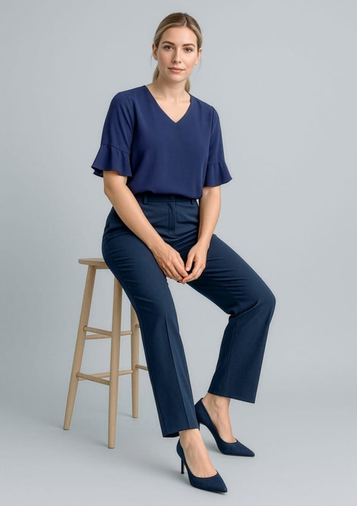 A woman sits on a stool wearing navy blue cool stretch adjustable waist pants and a matching navy top.