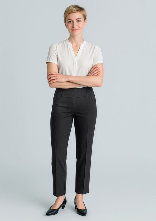 A woman wearing black slim leg pants and a white top, smiling with arms crossed. The pants feature a bandless design.