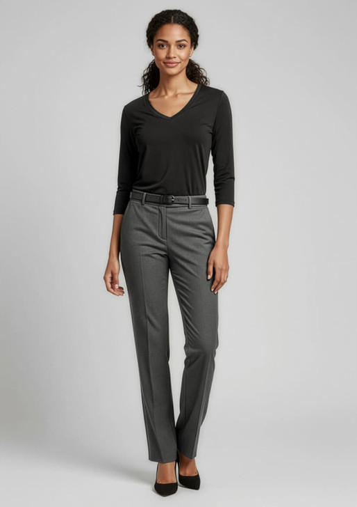 A woman wearing grey classic pants and a black top, with a belt, posing against a neutral background.