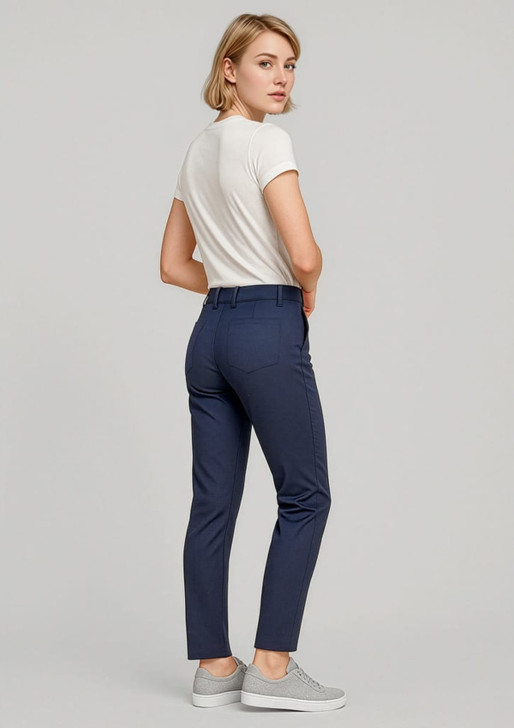 A woman stands wearing navy slim leg stretch chino pants and a white top, paired with grey sneakers.