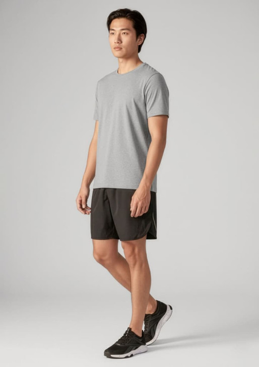 A man wearing a grey t-shirt and black sports shorts, paired with black athletic shoes. The outfit features a logo.