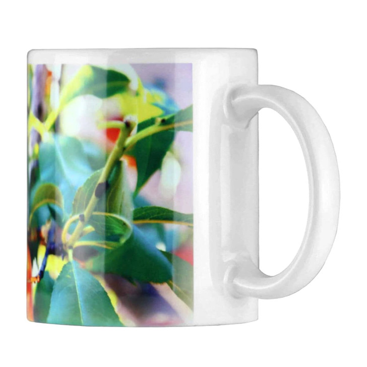 A white ceramic coffee mug featuring a vibrant, leafy design wrapped around its surface.