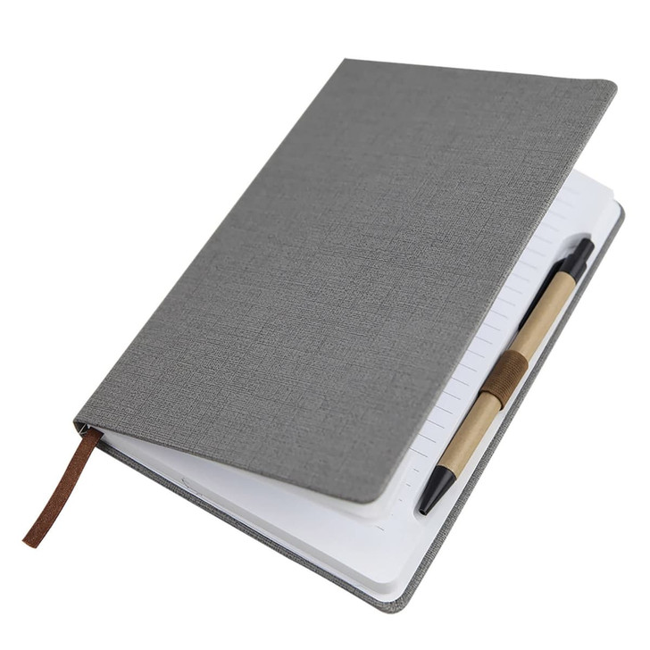 A5 textured grey PU notebook with a strap and a pen lying alongside it. The notebook features lined pages and a logo.