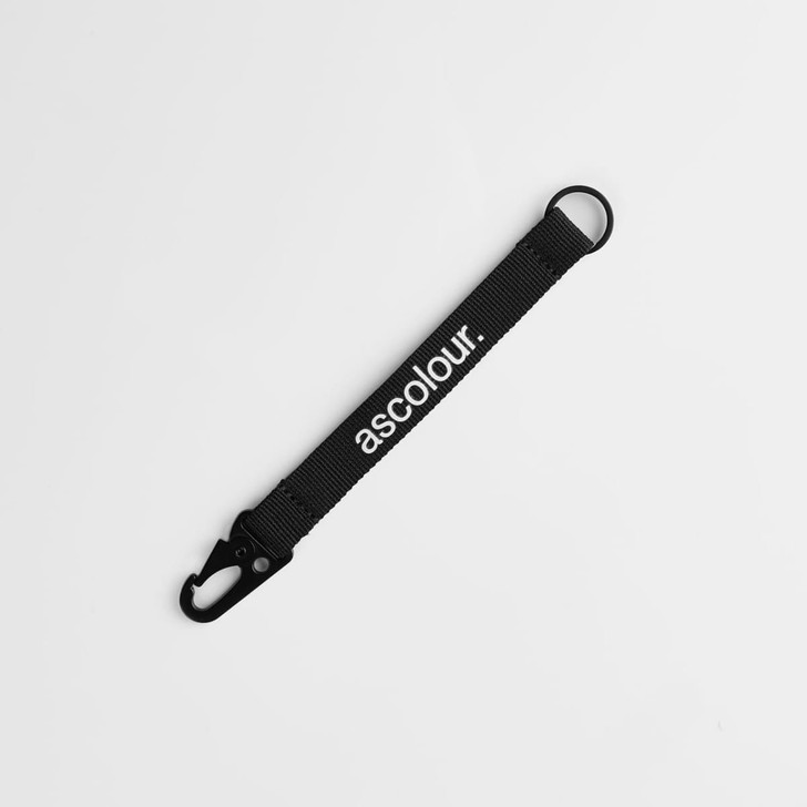 A black keychain made of fabric with a clip and a branding logo.