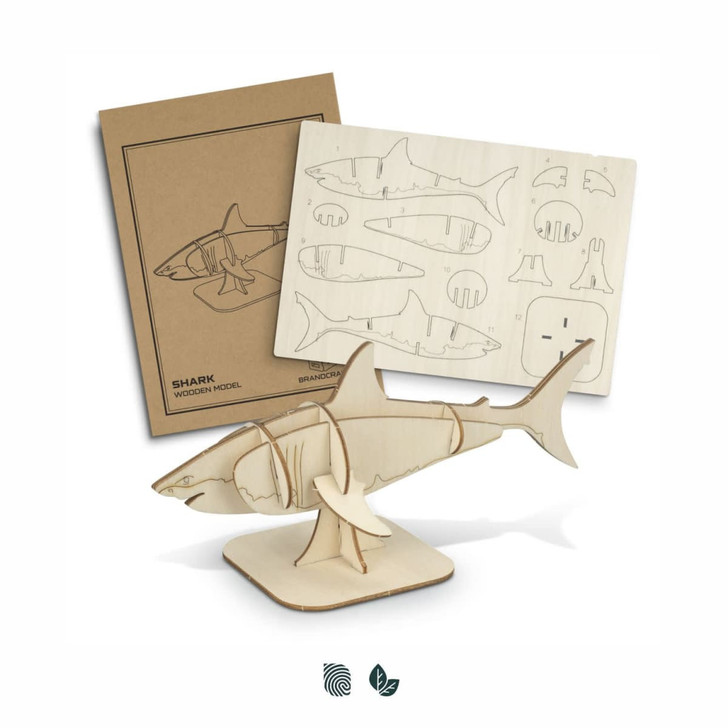 A wooden shark model in natural wood colour with assembly pieces and instructions displayed beside it.