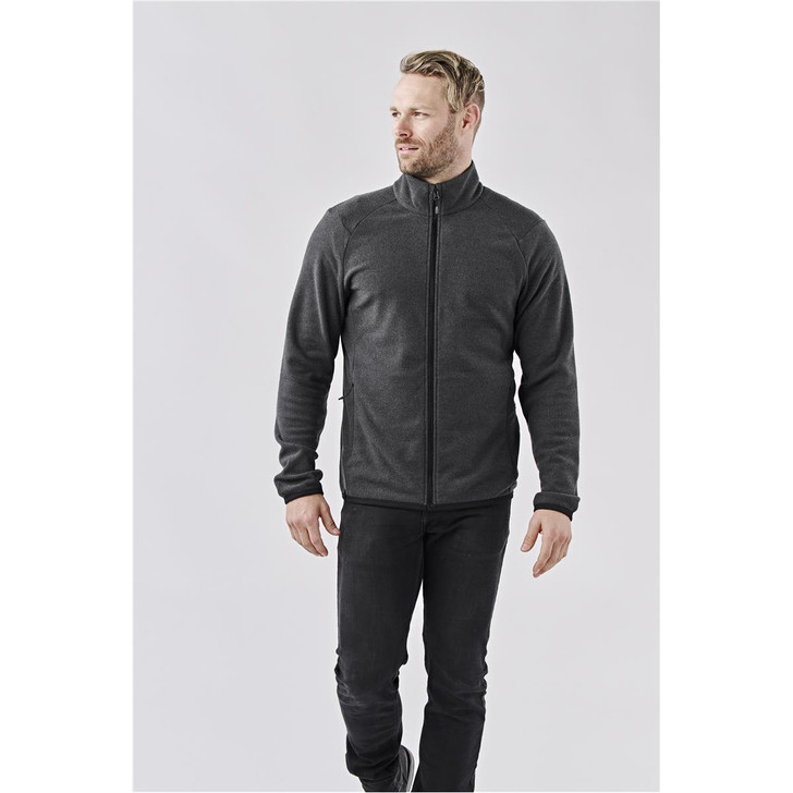 A men's full zip jacket in dark grey with a high collar and a fitted design. The jacket features a logo.