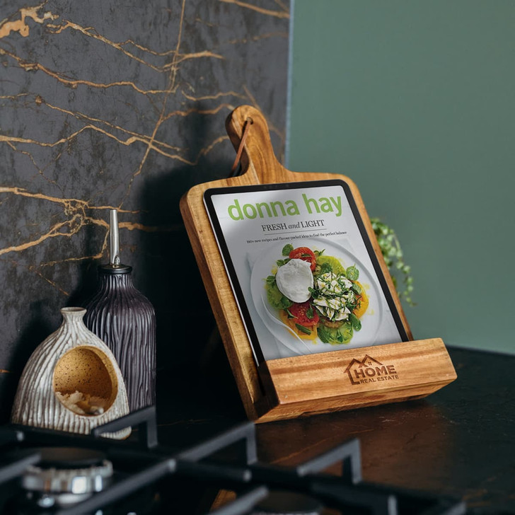 A wooden recipe book holder displaying a tablet with a vibrant salad image. Features a logo on the base.