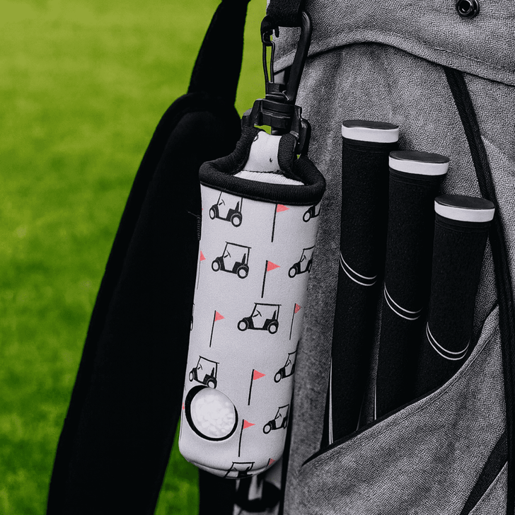A neoprene golf ball sleeve with a golf cart design, attached to a grey golf bag alongside black golf club grips.