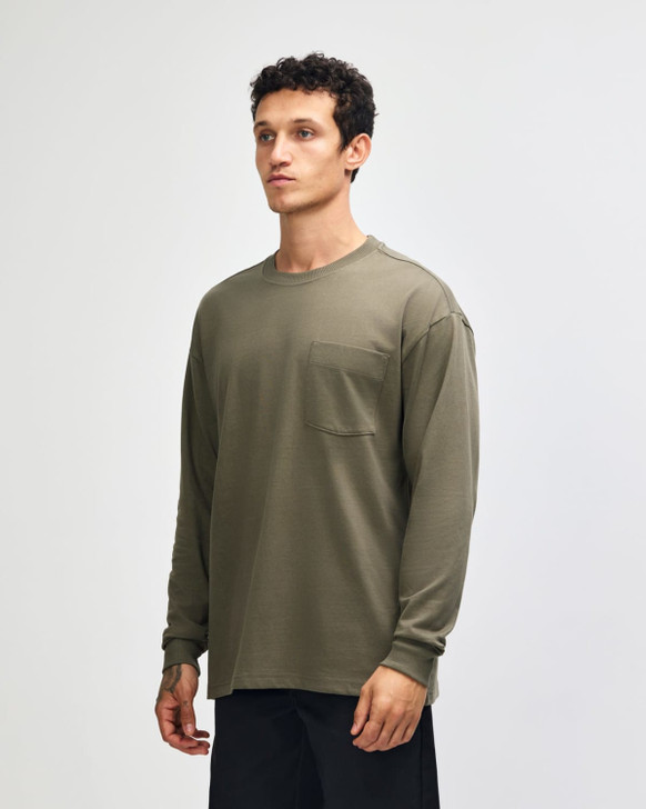 A long-sleeve, olive green t-shirt featuring a pocket and a logo, modelled by a young man.