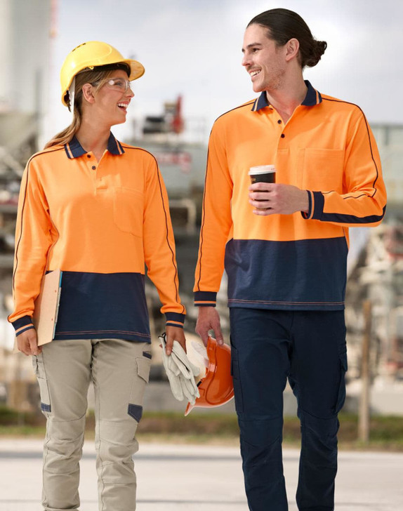 Two people walk side by side, wearing a hi-vis orange and navy blue long-sleeve polo shirt and safety gear.