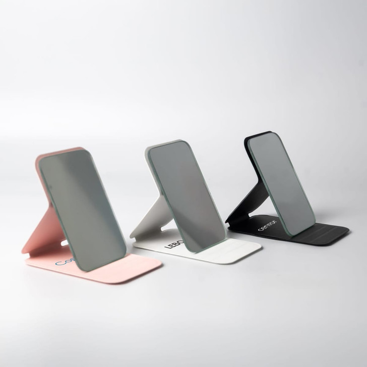 Three pocket mirrors in pink, grey, and black, each with a sleek, modern design and a stand.