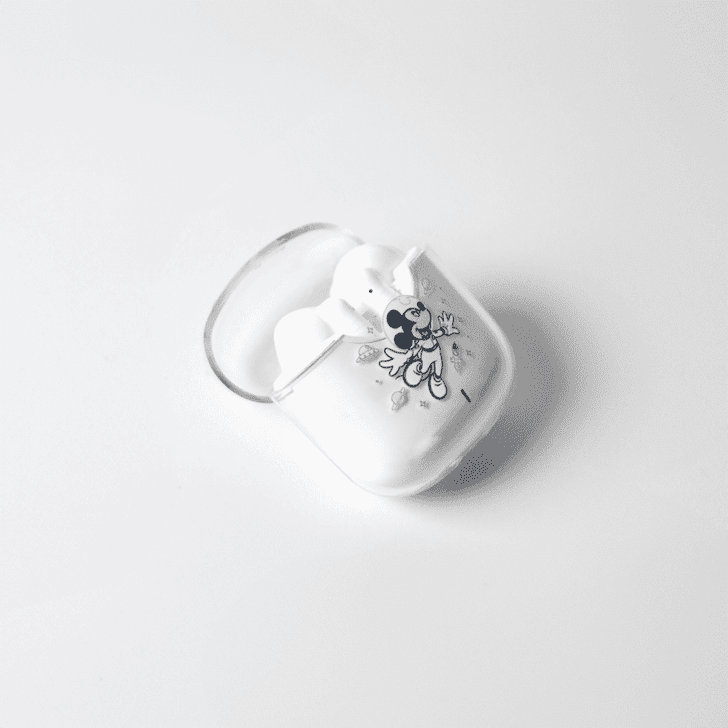 A pair of white noise cancellation earphones in a case featuring a playful design and a logo.