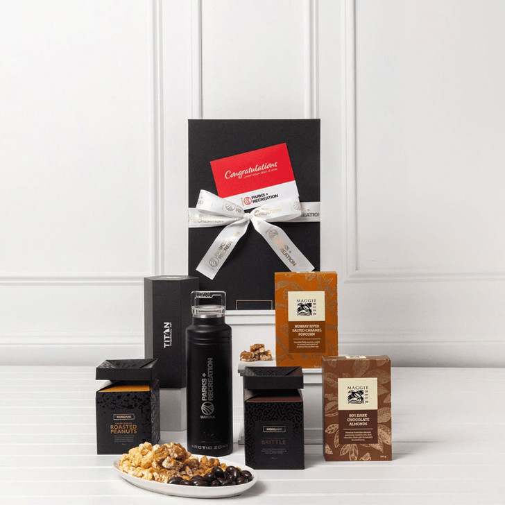 A black gift pack featuring a drink bottle, gourmet snacks, and assorted chocolates, presented with a decorative ribbon and card.