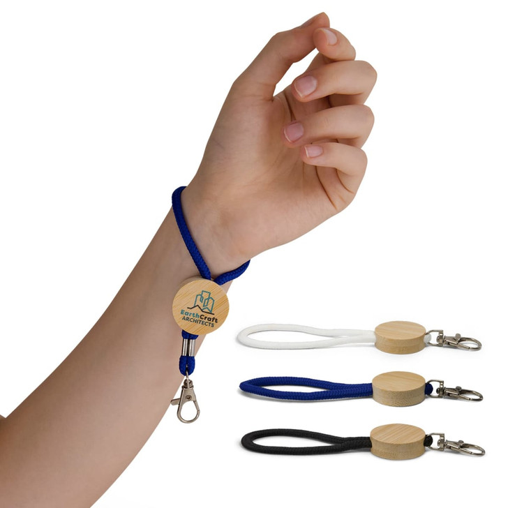 A hand holds a blue cord keytag with a wooden circular attachment, alongside black and white keytags.