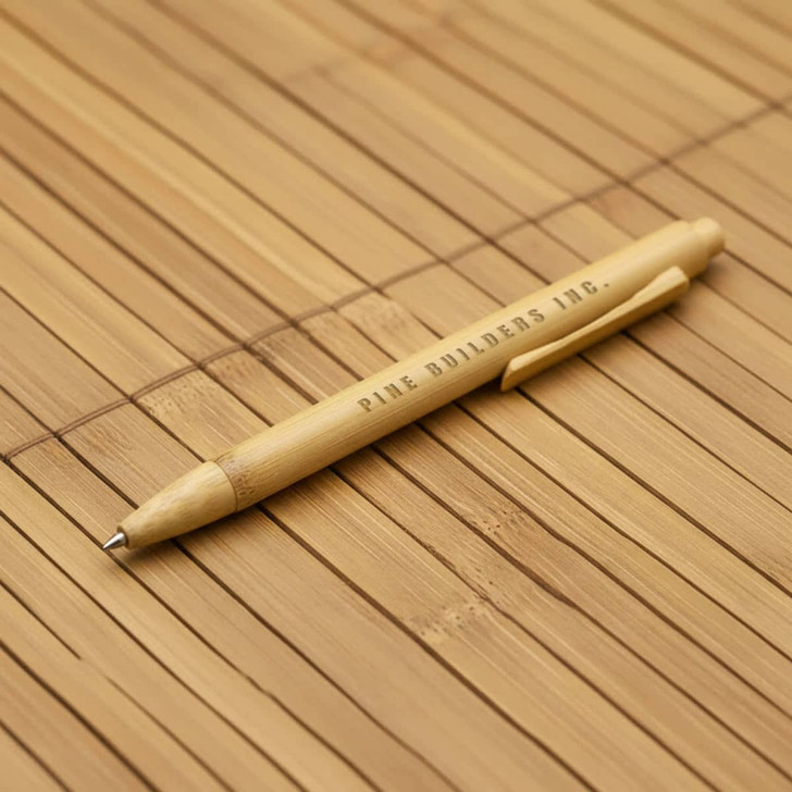 A bamboo pen with a natural finish, featuring a clip and branding. The background is made of bamboo material.